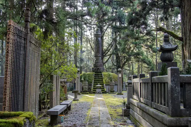 Sendero entre cedros, con lápidas cubiertas de musgo y faroles de piedra, en el cementerio de Okunoin