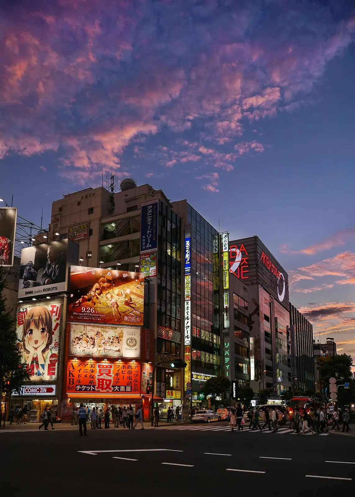 Edificios de Akihabara llenos de carteles de anime bajo un cielo rosa al atardecer, en Tokio