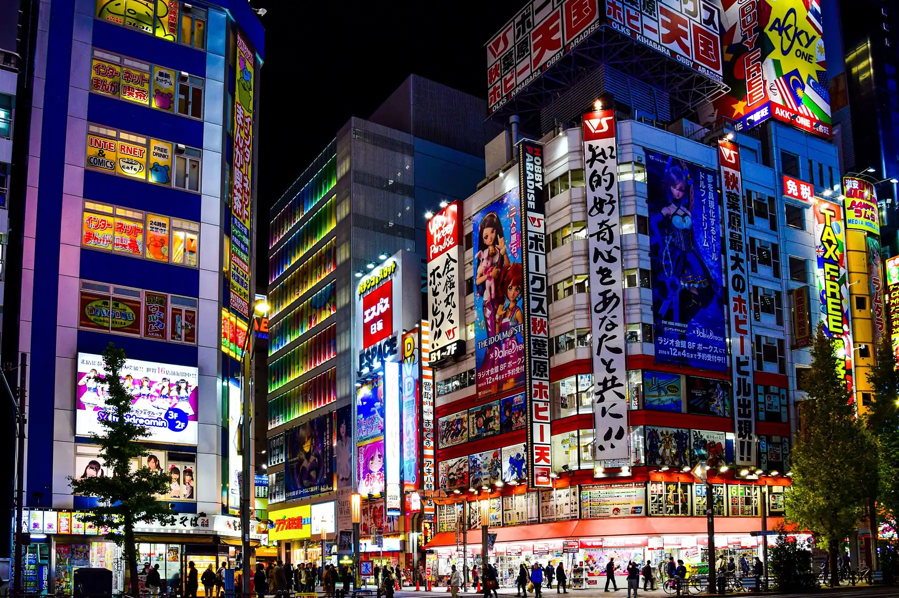 Fachadas de Akihabara iluminadas de noche, con grandes carteles de anime y tiendas de figuras, en Tokio