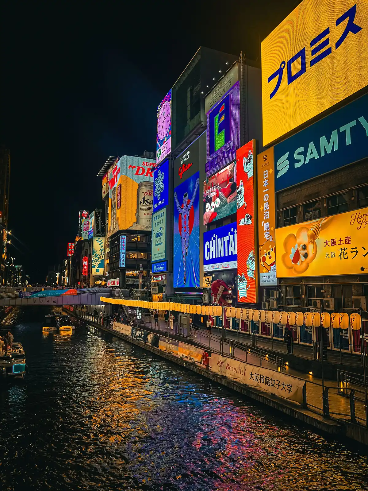El canal de Dotonbori de noche, con pantallas gigantes reflejadas en el agua, en Osaka