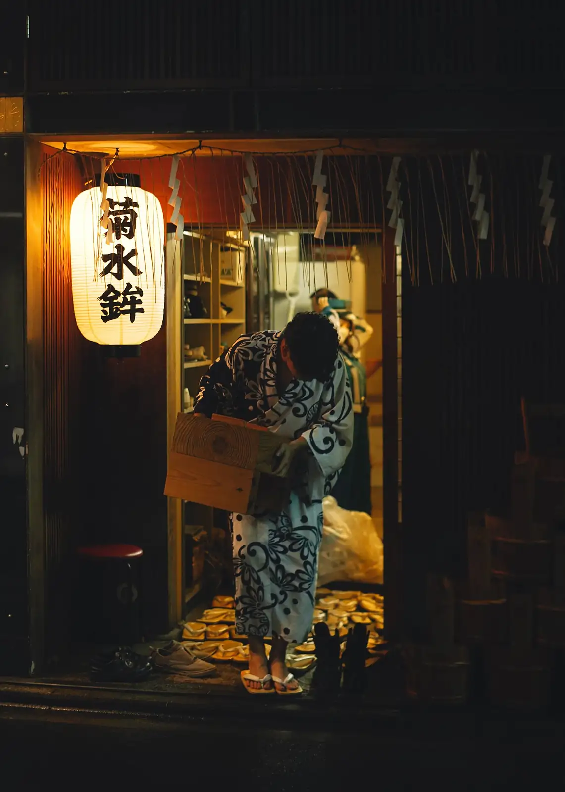 Un hombre en yukata a la entrada de un local tradicional de Kioto, de noche