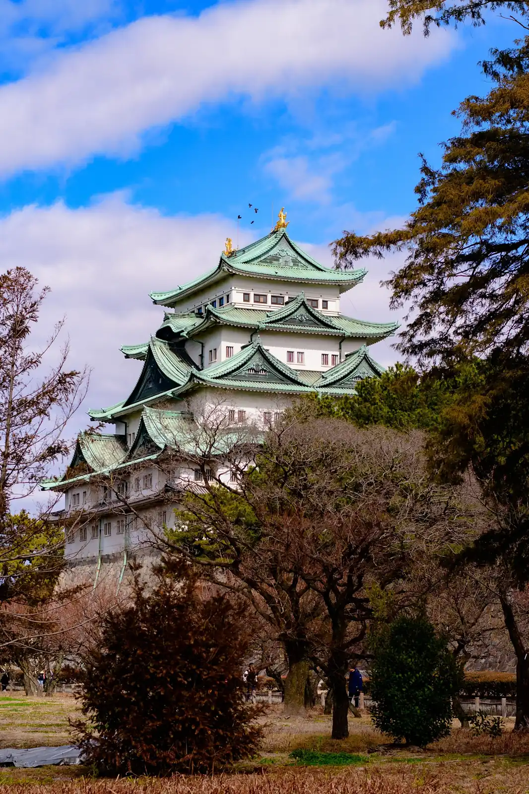 El castillo de Nagoya, con sus tejados verdes, entre árboles y bajo un cielo azul