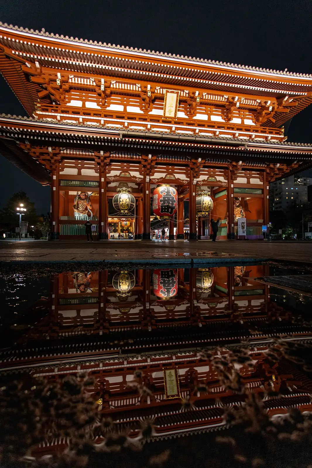 La gran puerta del templo Senso-ji de noche, reflejada en el suelo mojado, en Tokio